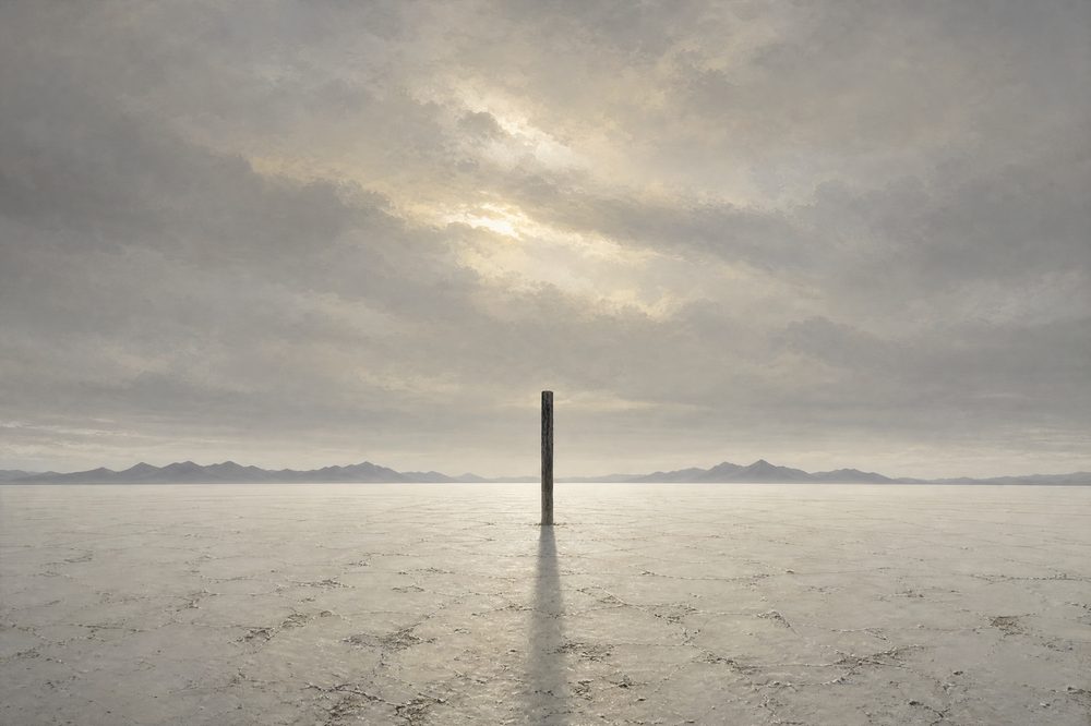 A vast pale salt flat under high overcast with a single dark upright post at the exact centre casting a long thin shadow toward the viewer and a faint mountain range on the horizon